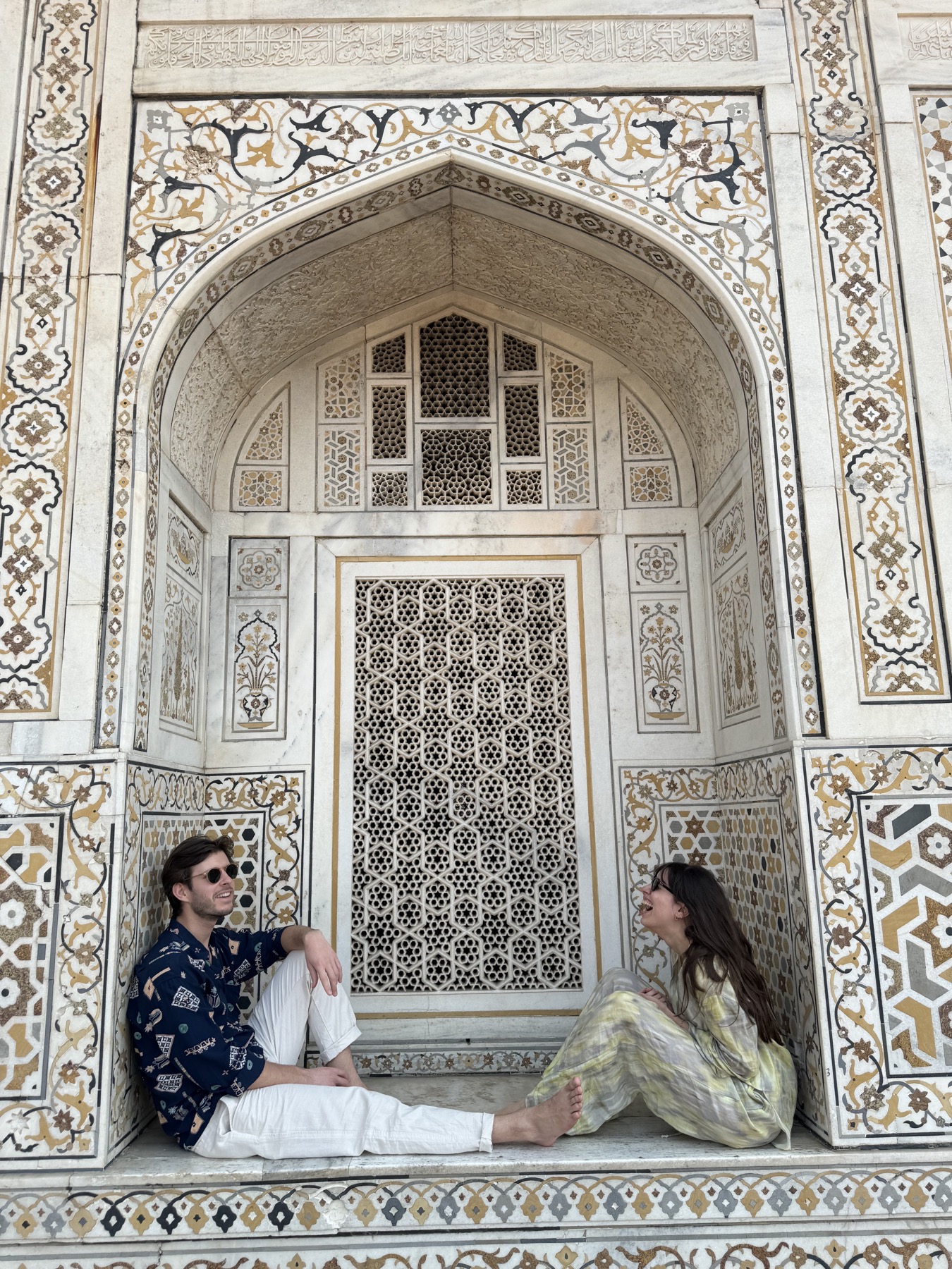 Giuliana and Arthur laughing together beneath an ornate arch